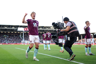 Football player walks past man with tv camera